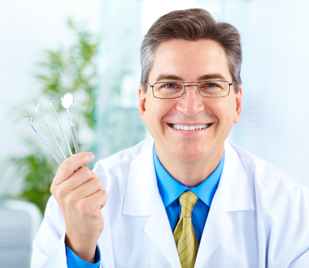 Smiling Dentist With Tools In The Office