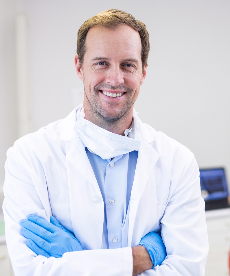 Portrait Of Dentist Standing With Arms Crossed In Clinic